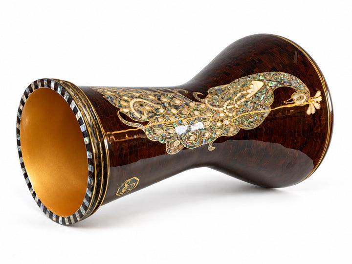 Sala Amber Peacock Sombaty darbuka on its side, showing the open base and a pale peacock motif on a dark amber-brown mosaic background.